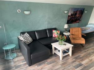 a living room with a black couch and a table at Amsterdam Countryside met Airco , luxe keuken en een geweldig uitzicht, Immer besser! in Den Ilp