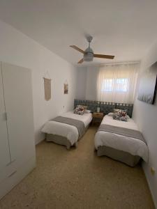 Cette chambre dispose de 2 lits et d'un ventilateur de plafond. dans l'établissement Trimar - Apartamento céntrico con garaje, à Fuengirola