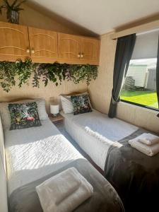 a bedroom with two beds in a caravan at Jungle House no.26 at Three Lochs Holiday Park in Newton Stewart