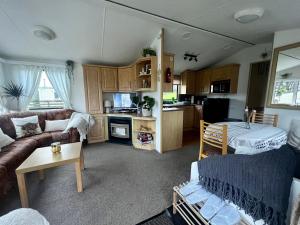 a living room with a couch and a kitchen at Jungle House no.26 at Three Lochs Holiday Park in Newton Stewart