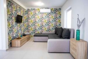 uma sala de estar com um sofá e papel de parede floral em Verandás Vendégház em Hajdúnánás
