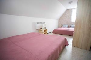 um quarto com uma cama rosa e uma parede de tijolos em Verandás Vendégház em Hajdúnánás