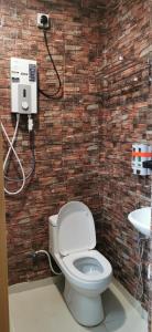 a bathroom with a toilet and a brick wall at Tang Hotel in Alor Setar