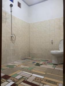 baño con aseo y suelo de baldosa. en Bintang Guesthouse, en Gili Trawangan