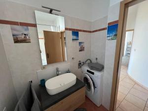ein Badezimmer mit einem Waschbecken und einer Waschmaschine in der Unterkunft Traumwohnung am Altstadt Hafen Stralsund in Stralsund