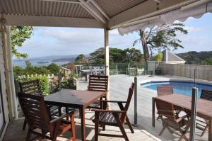 un patio con mesa, sillas y piscina en Kauri Villas en Parua Bay