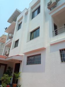un bâtiment blanc avec des fenêtres et des plantes dans l'établissement Janaki House, à Katmandou