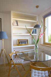 een woonkamer met een glazen tafel en een vaas met bloemen bij Signe Home in Gdańsk