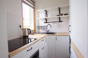 a kitchen with white cabinets and a sink and a window at Signe Home in Gdańsk