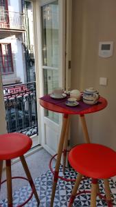 una mesa roja y dos taburetes delante de una puerta en Porto with History, en Oporto