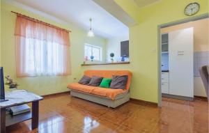 an orange couch in a living room with a clock at Nice Apartment In Marcana With Wifi in Marčana