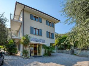 a large white building with palm trees in front of it at Hotel Silvana Garnì in Limone sul Garda