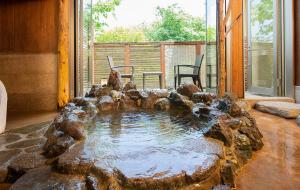 einen Pool mit Wasser in einem Zimmer mit Felsen in der Unterkunft Bettei Soan in Minami Aso