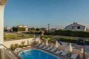 a view of a swimming pool with chairs and umbrellas at APARTMANI JAMAN in Vrsi