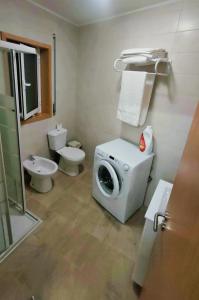 uma casa de banho com uma máquina de lavar roupa e um WC em Casa da Clarinha em Castelo de Paiva