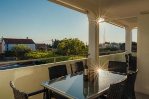 a balcony with a glass table and chairs at APARTMANI JAMAN in Vrsi