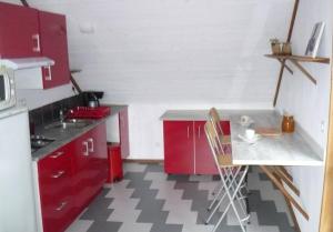 a small kitchen with red cabinets and a table at T3 ecolo en campagne in Le Roc-Saint-André