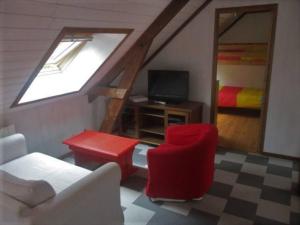 a living room with a couch and a red chair at T3 ecolo en campagne in Le Roc-Saint-André