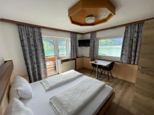 a bedroom with a bed and a desk and two windows at Hotel-Garni Seestrand in Zell am See