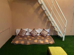 a bed with four pillows sitting under a staircase at Art House- Air conditioned luxury service Apartments in Bangalore