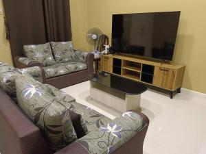 a living room with two couches and a flat screen tv at Guesthouse 26 Villa/Sejati/Mile7 in Sandakan