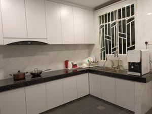 a kitchen with white cabinets and a counter top at Guesthouse 26 Villa/Sejati/Mile7 in Sandakan