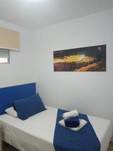 Un dormitorio con una cama blanca con un asiento azul y una foto en Apartamentos Playamar en Isla Plana