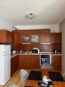 Summer Host Apartment Onegin في سوزوبول: مطبخ بدولاب خشبي وطاولة مع كراسي