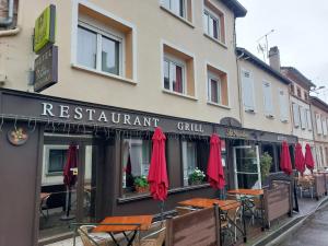 Logis Hôtel - Les Pasteliers في لافاور: مطعم فيه مظلات حمراء امام مبنى