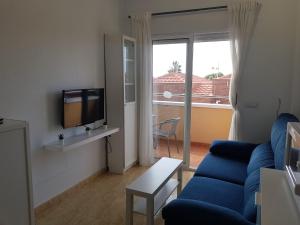 Apartamentos Playamar في إسلا بلانا: غرفة معيشة مع أريكة زرقاء وتلفزيون