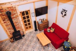 a living room with a red couch and a fireplace at Domek Sówka na Kociewiu in Nowy Wiec