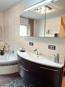 a bathroom with a sink and a tub and a mirror at Panorama-Residenz, mit Pool in Bad Koetzting