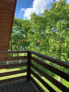 a wooden porch with a fence and trees in the background at Dom na Mazurach in Stare Juchy