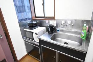 a small kitchen with a sink and a microwave at アンドステイ中野5丁目203 in Tokyo +39 photos