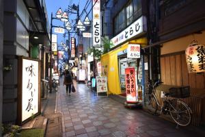 a woman walking down a street in an asian city at アンドステイ中野5丁目203 in Tokyo
