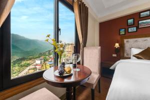 ein Hotelzimmer mit einem Bett und einem Tisch mit einem Fenster in der Unterkunft Tiger Sapa hotel in Sa Pa
