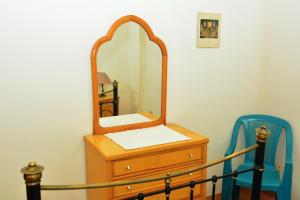 einen Spiegel auf einer Kommode mit einem blauen Stuhl in der Unterkunft Villa Belzoni in Luxor