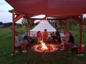 a group of people sitting around a fire in a gazebo at La petite ferme de Pouillon - Parc animalier - aire de loisirs in Pouillon