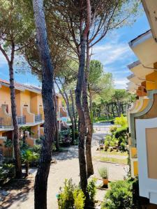 vista sul cortile di un resort alberato di Villetta le Rondini a Lignano Sabbiadoro