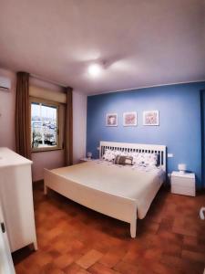 una camera con un grande letto con una parete blu di la finestra sul mare a marzamemi a Marzamemi