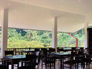 a dining room with tables and chairs and a large window at Hotel Gangaaddara in Kandy