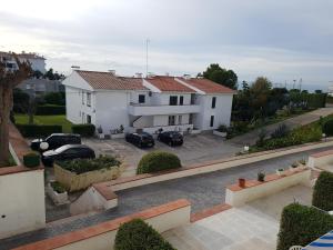 a white house with cars parked in a parking lot at Sitges - Apartamento in Sitges