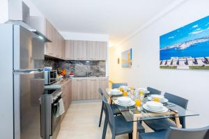 a kitchen with a dining table with chairs and a refrigerator at Islet Promenade Seafront Family Apartment with 2 balconies by Getawaysmalta in St Paul's Bay +47 photos