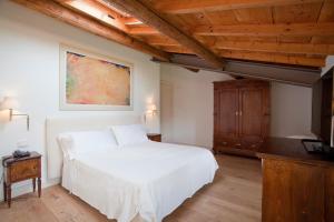 a bedroom with a white bed and a wooden ceiling at Relais Corte Guastalla Apartments in Sona