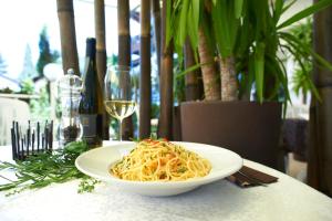 un piatto di pasta su un tavolo con un bicchiere di vino di Hotel Ladurner a Merano