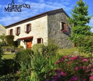 una casa de piedra con un jardín delante de ella en A Cantaruxa Maruxa Turismo Rural en Mondariz