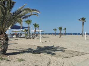 a beach with palm trees and umbrellas and the ocean at Apartamento en playa arenal de Burriana in Burriana