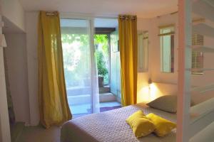 Cette chambre comprend un lit avec des rideaux jaunes et un balcon. dans l'établissement Nature calme piscine privée chauffée 7 jours minimum, à Brullioles