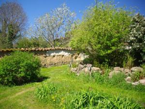 a garden with a stone wall and trees and grass at Nature calme piscine privée chauffée 7 jours minimum in Brullioles