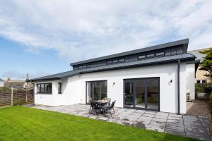 a white house with a black roof and a patio at The Hideaway, Modern 3 bed in Tintagel, Cornwall in Tintagel